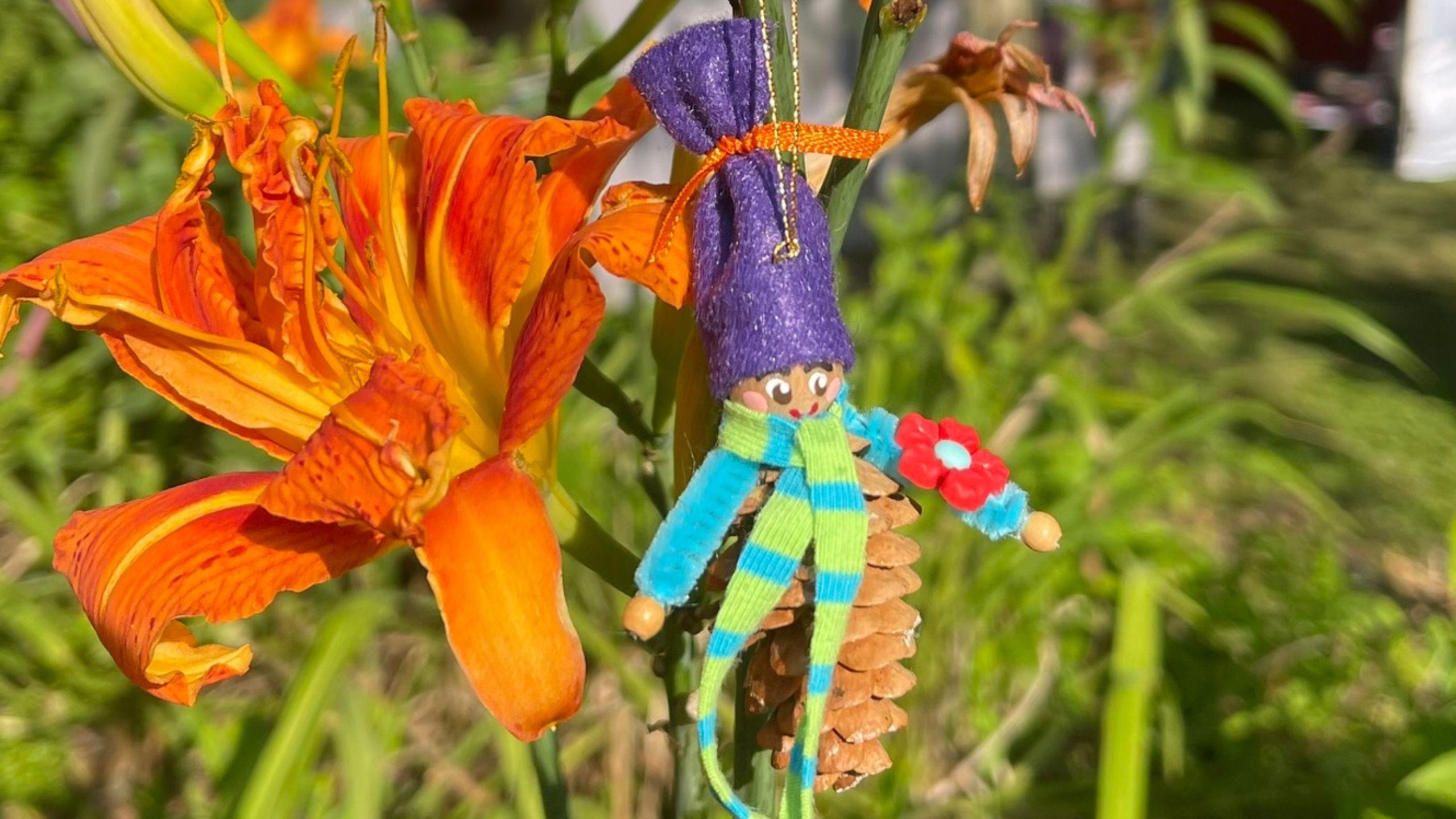 Pinecone Gnome in garden next to orange lily.